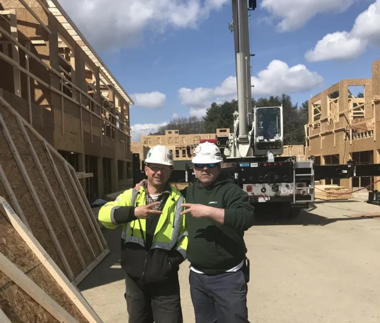 Dave Snyder and a crew member in hard hats on a job site, with a DJ Snyder crane truck behind them